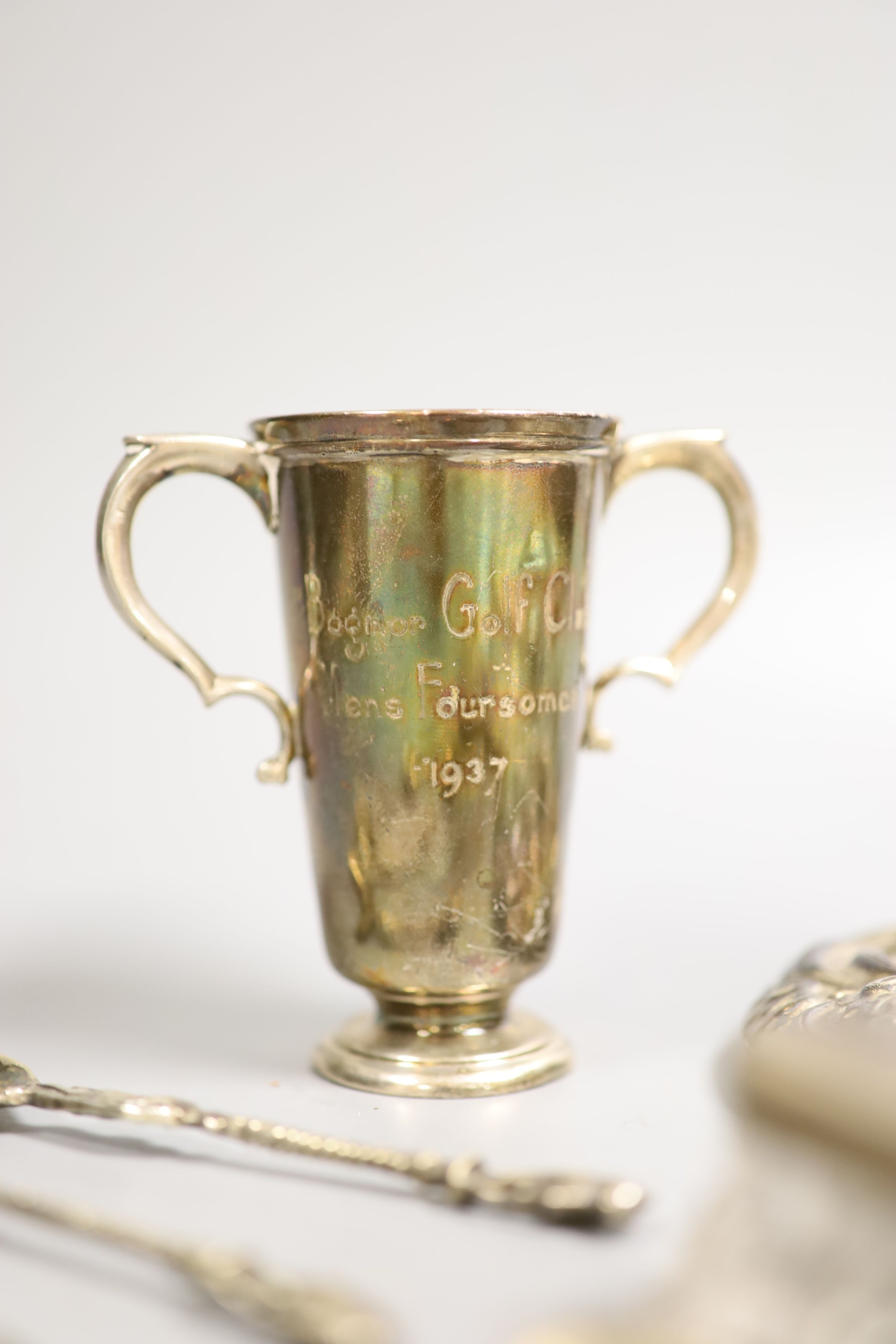 Small silver including a hand mirror, two mounted glass toilet jars, two handled golfing related trophy cup, silver spoons, white metal and enamel dish etc.